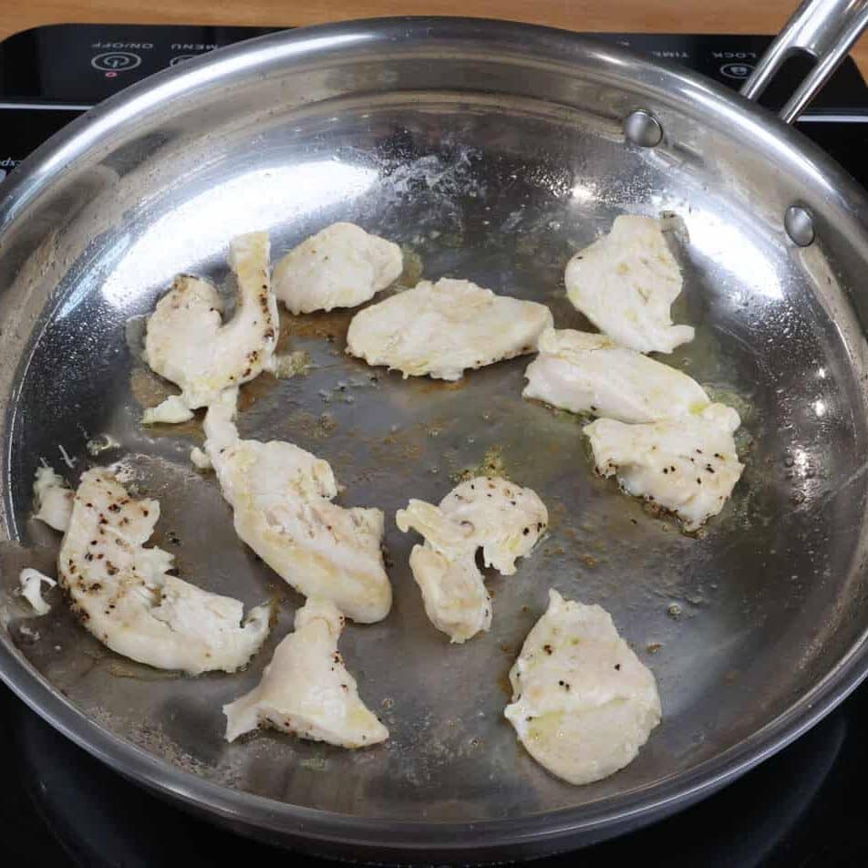 chicken strips cooking in a small skillet.