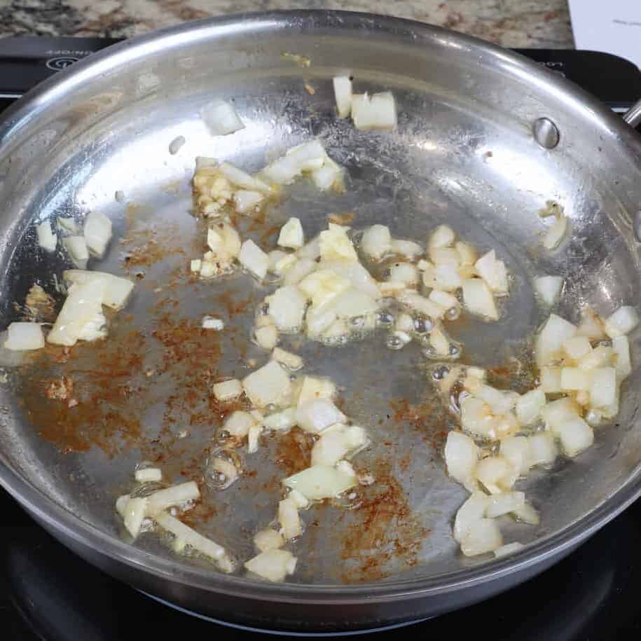 chopped onions and garlic cooking in a skillet.