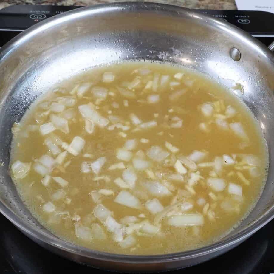 chicken broth simmering in a pan on the stove.