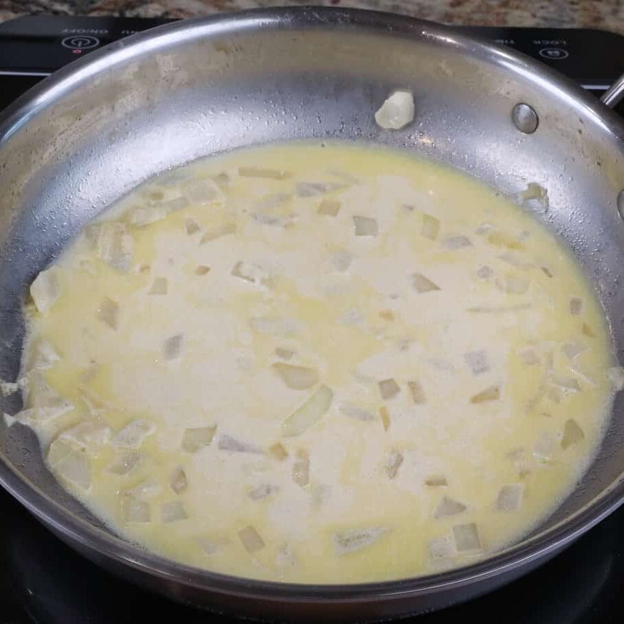 chicken divan sauce in a pan simmering on the stove.