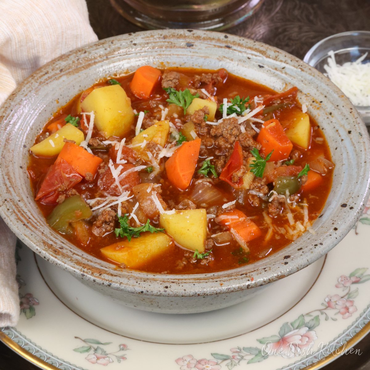 a bowl of hamburger soup topped with parmesan cheese.