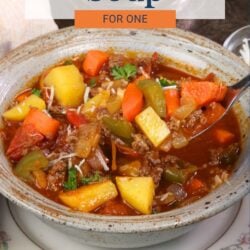 a bowl of hamburger soup with a spoon on the side.