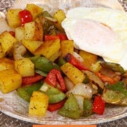 O'Brien Potatoes on a white plate with a fried egg on top.