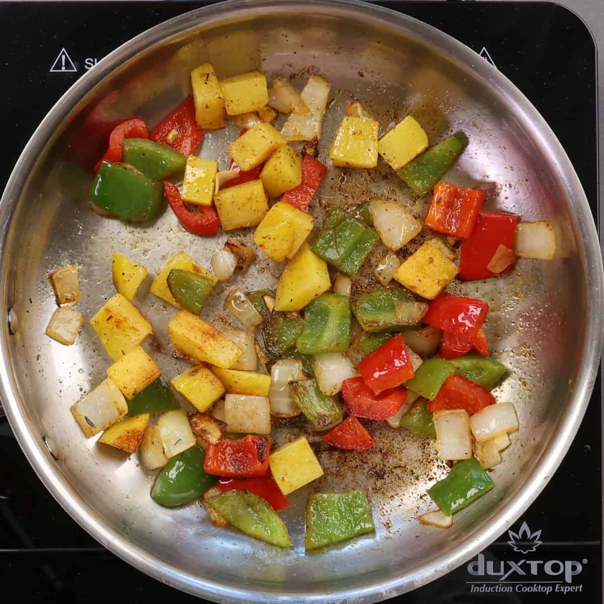 diced potatoes browning in a skillet along with peppers and onions.