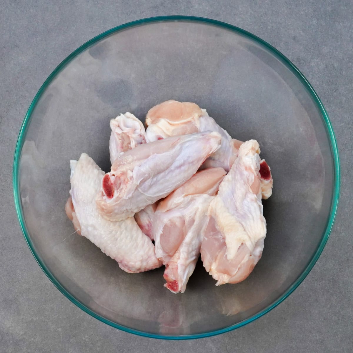 a bowl filled with raw chicken wings.