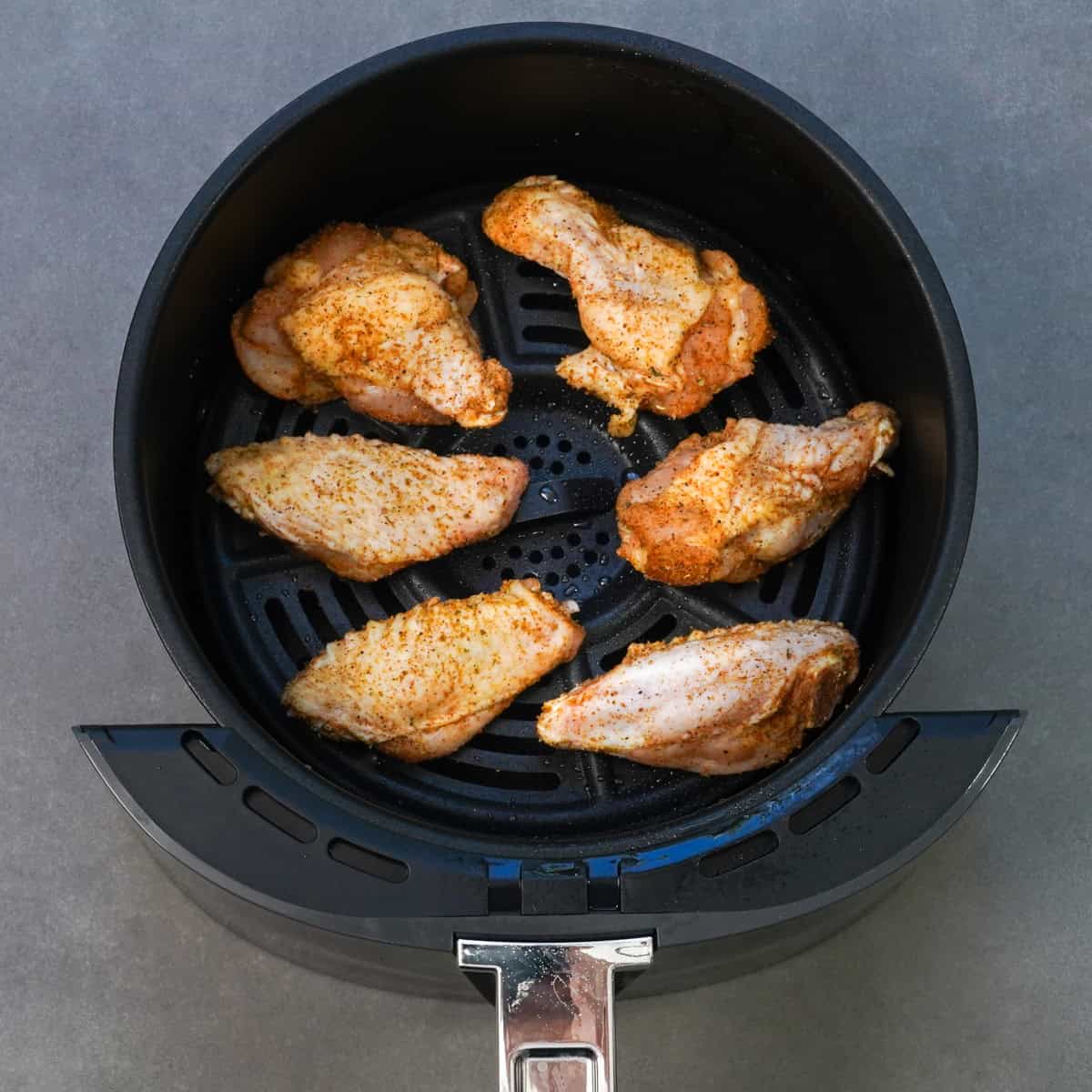 six chicken wings in an air fryer.