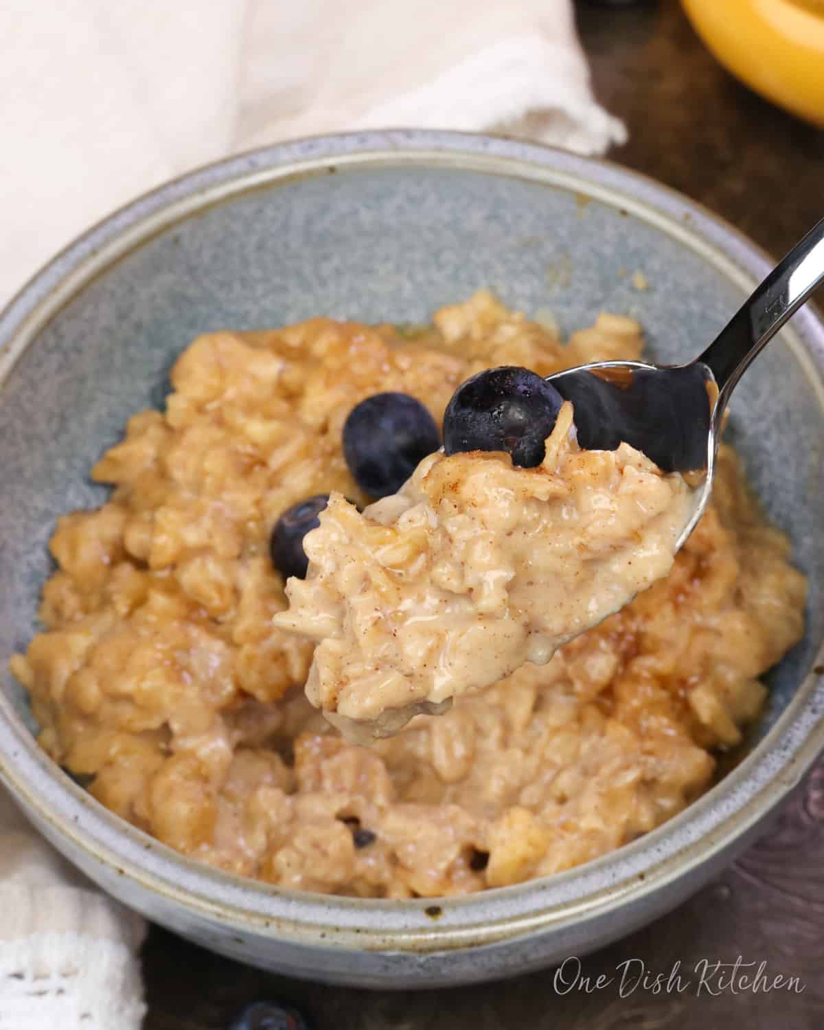 a blue bowl filled with peanut butter oatmeal with a spoon on the side.