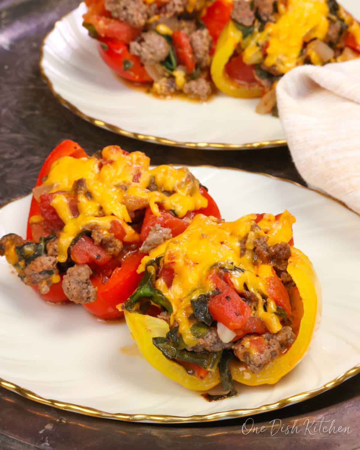 four stuffed pepper halves on two plates.