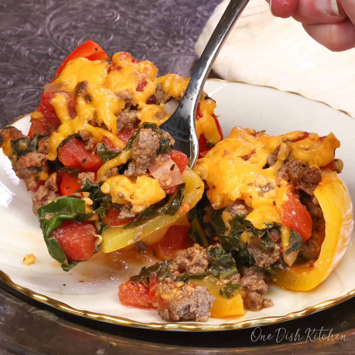 two stuffed peppers on a plate with a fork on the side.