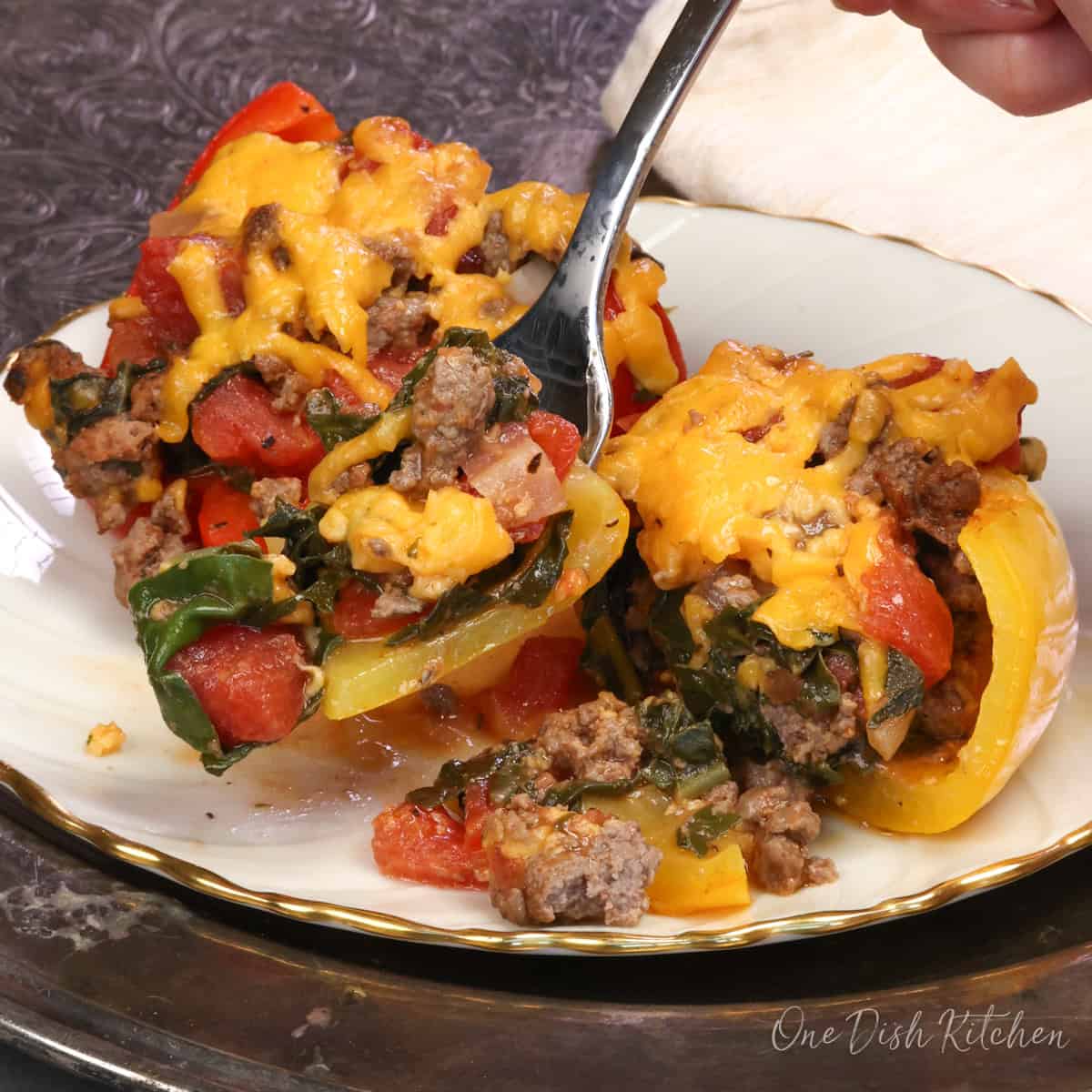 two stuffed peppers with a fork on the side of the plate.