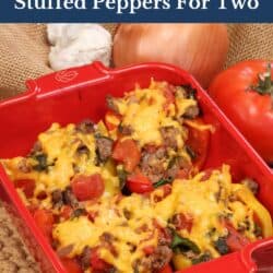 four stuffed pepper halves in a red baking dish.