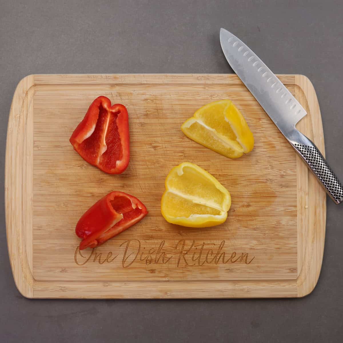 two bell peppers sliced in half on a cutting board.