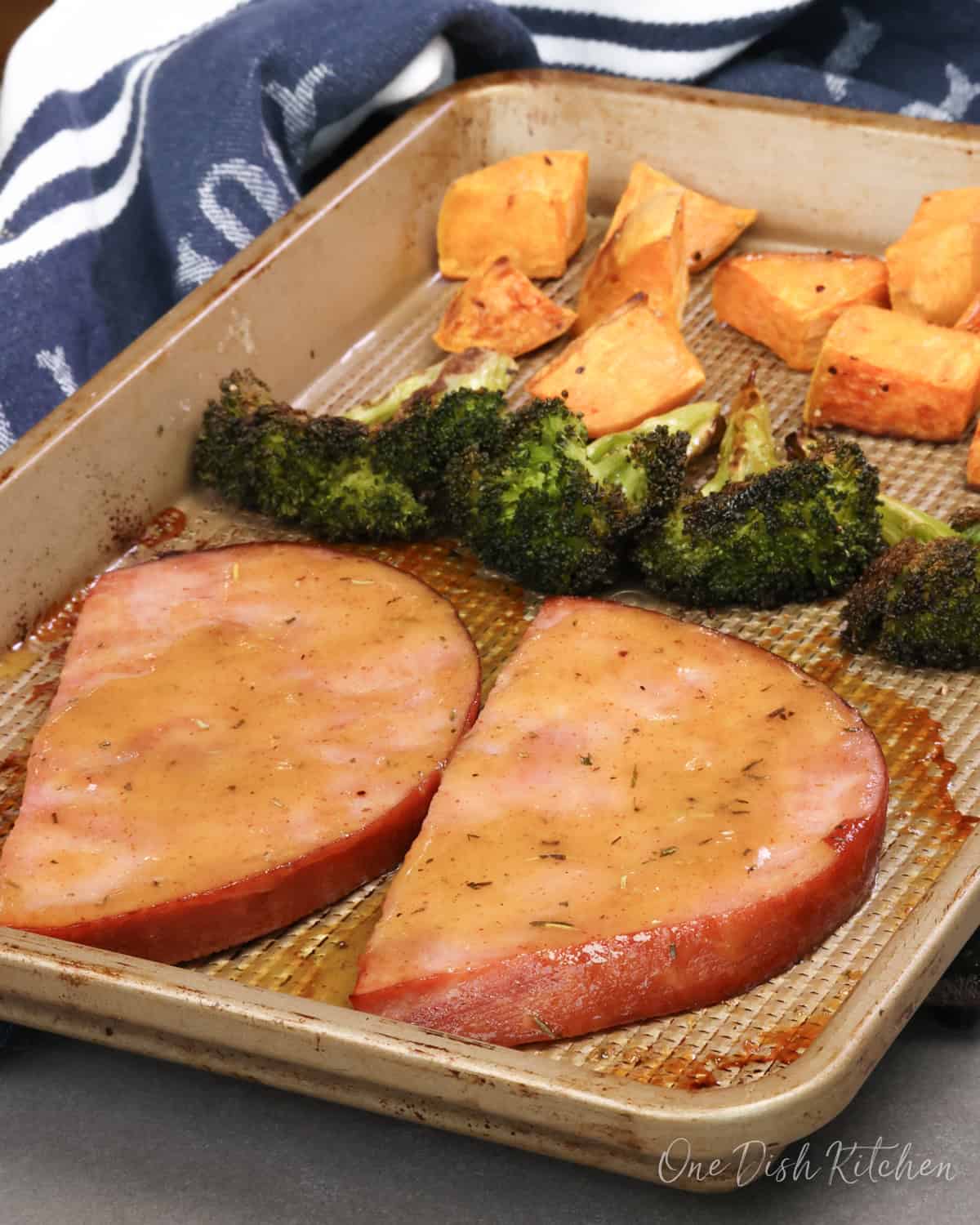 baked ham steaks on a sheet pan with roasted vegetables.