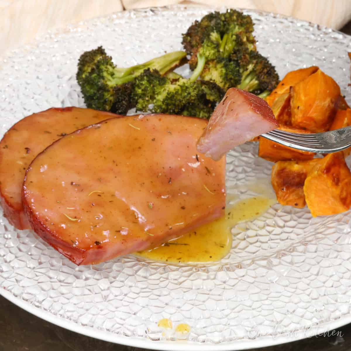 ham steak sliced on a plate next to roasted vegetables.