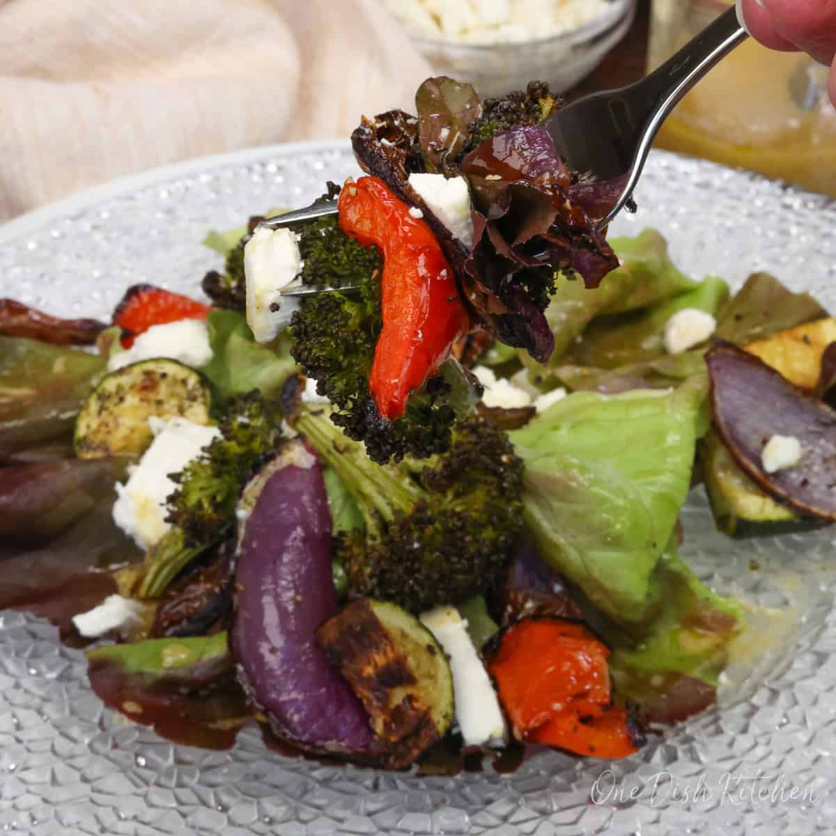 roasted vegetables on top of salad greens with a fork on the side.