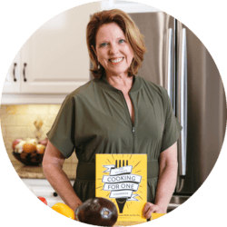 Joanie Zisk, chef and author of The Ultimate Cooking for One Cookbook, holding her cookbook.