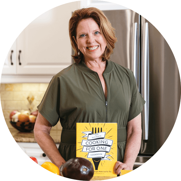 women in green dress standing and holding a cookbook.