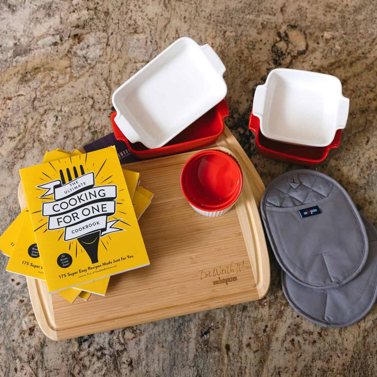 rectangle baking dishes, ramekins, cutting board and cookbook on counter.