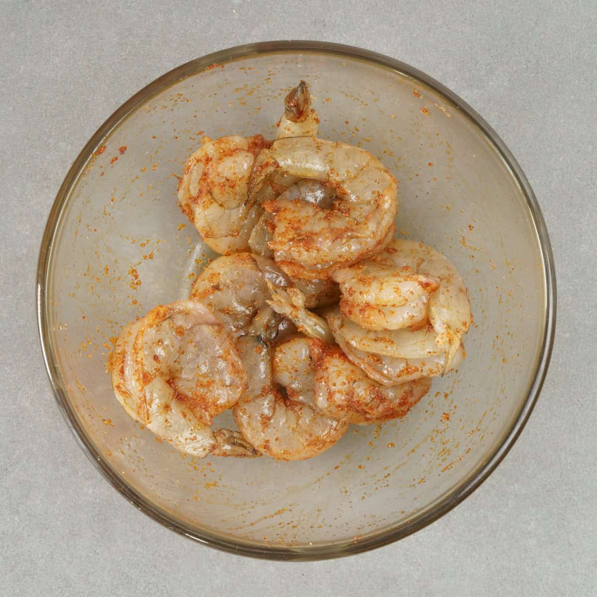 raw shrimp tossed with seasonings in a bowl.