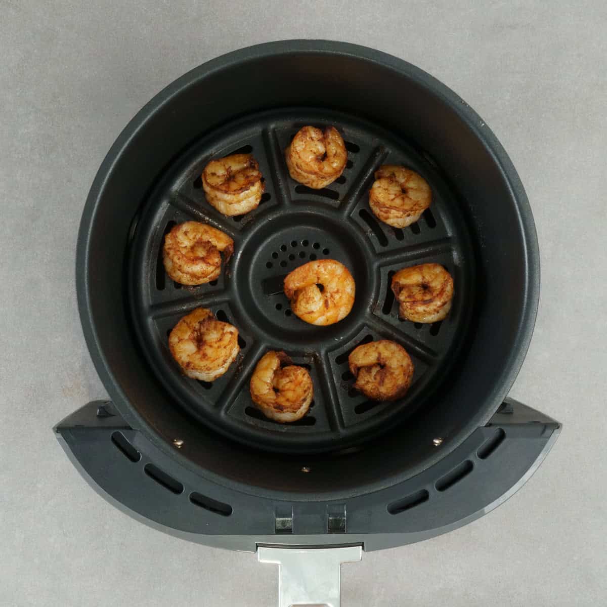 a small batch of cooked shrimp in an air fryer basket.