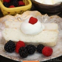 two slices of angel food cake on a white plate topped with whipped cream and surrounded by berries.