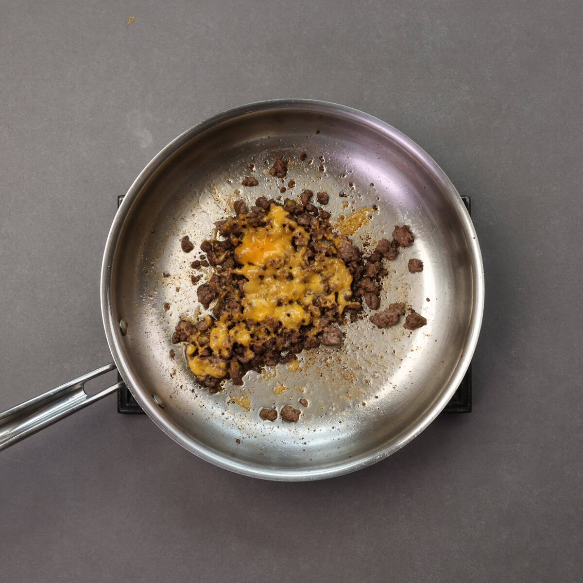 cooked ground beef with melted cheese in a skillet.