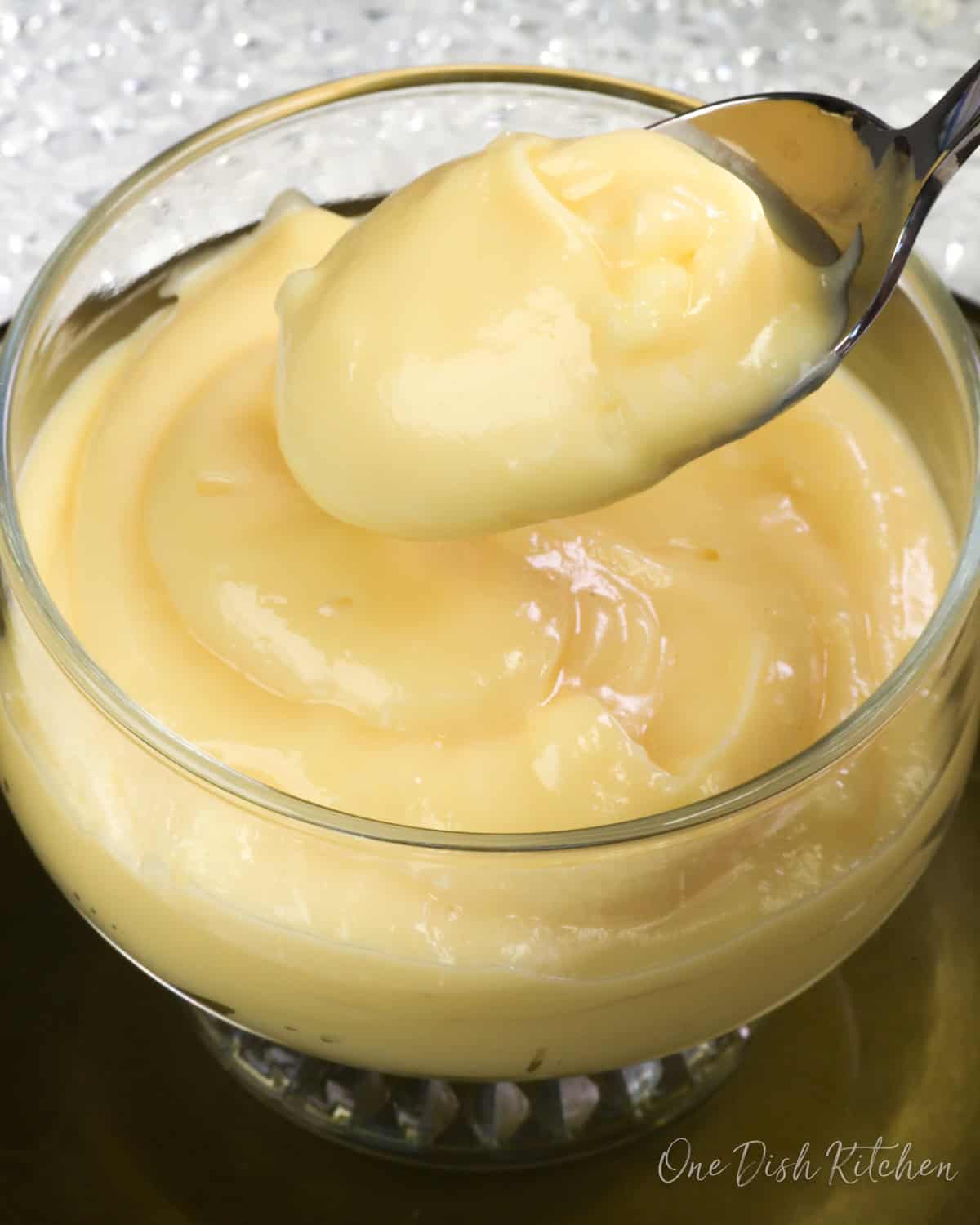 a bowl of vanilla custard with a spoon on the side.