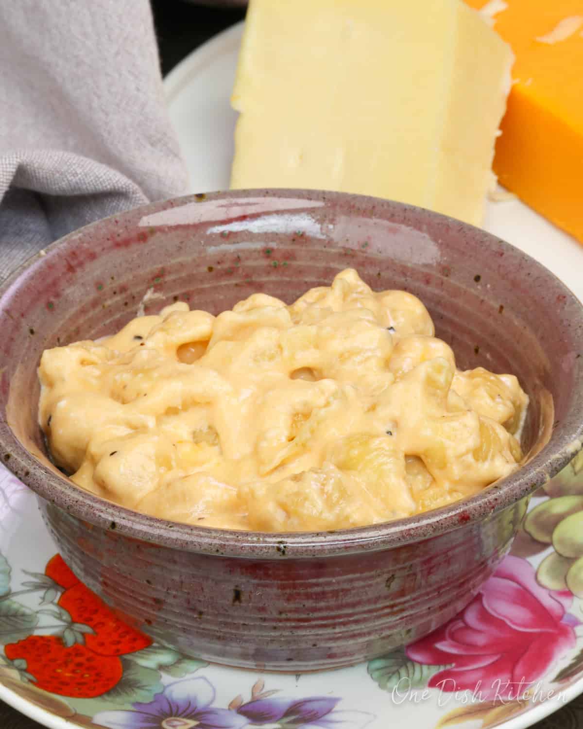 a bow of creamy mac and cheese next to a brown napkin.
