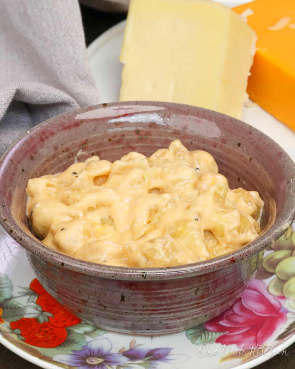a bow of creamy mac and cheese next to a brown napkin.