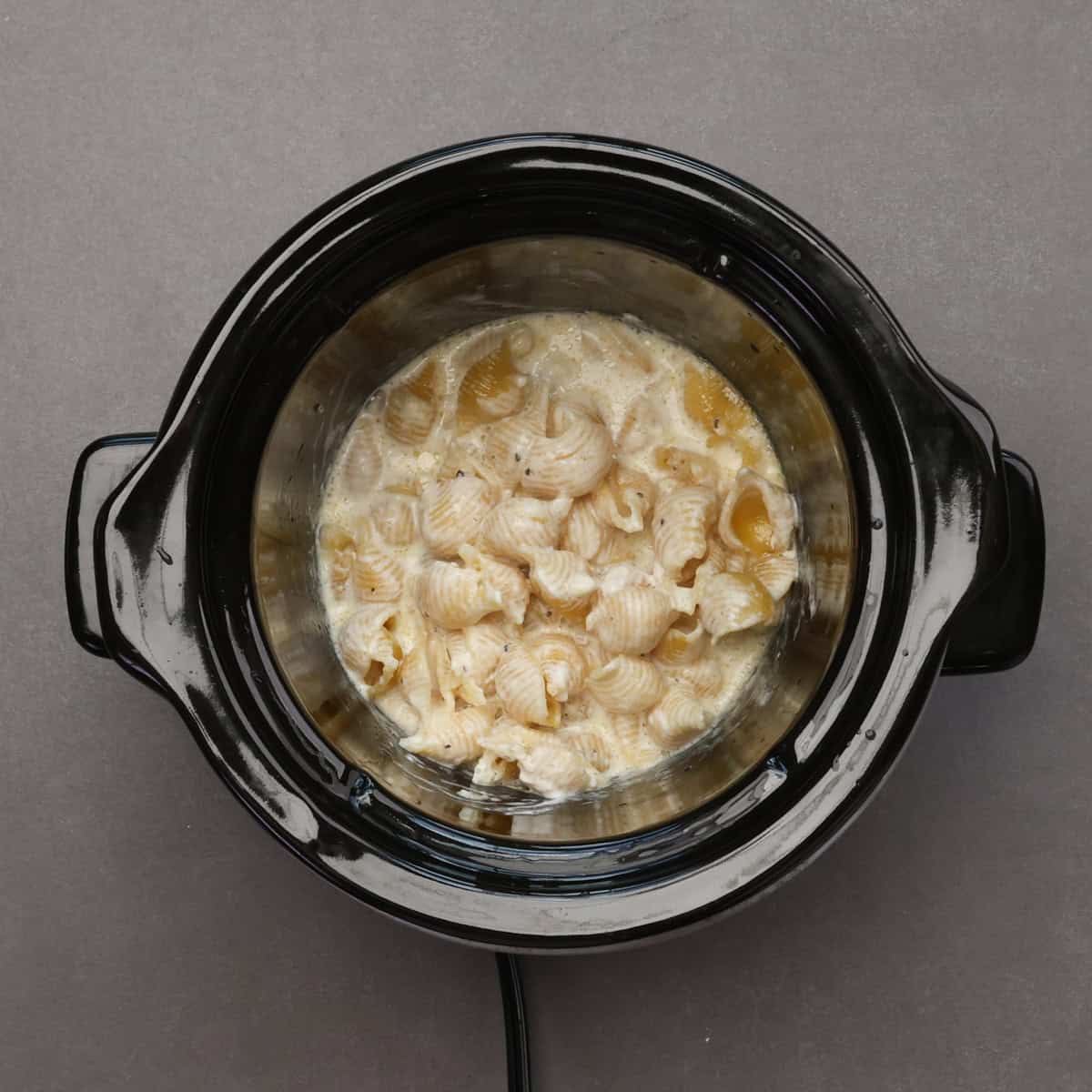 macaroni cooking in milk and cream in a slow cooker.