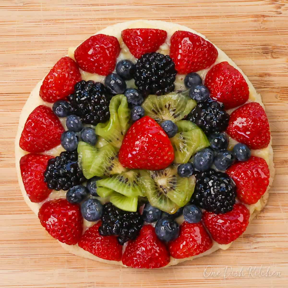 a small tart topped with fresh fruit on a cutting board.