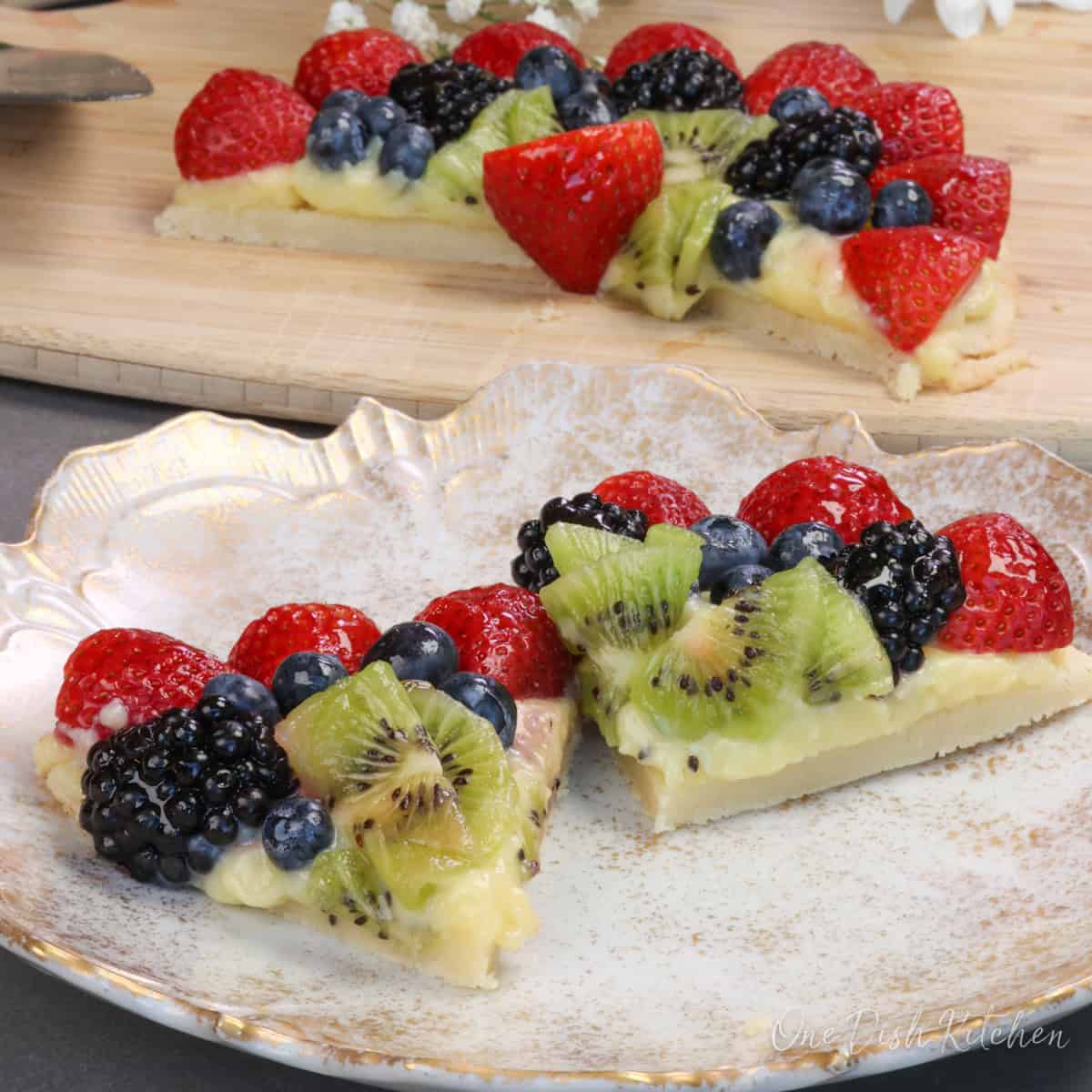 a small fruit tart sliced into quarters on a white plate.