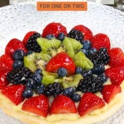 a small fruit tart sliced into quarters on a white plate.
