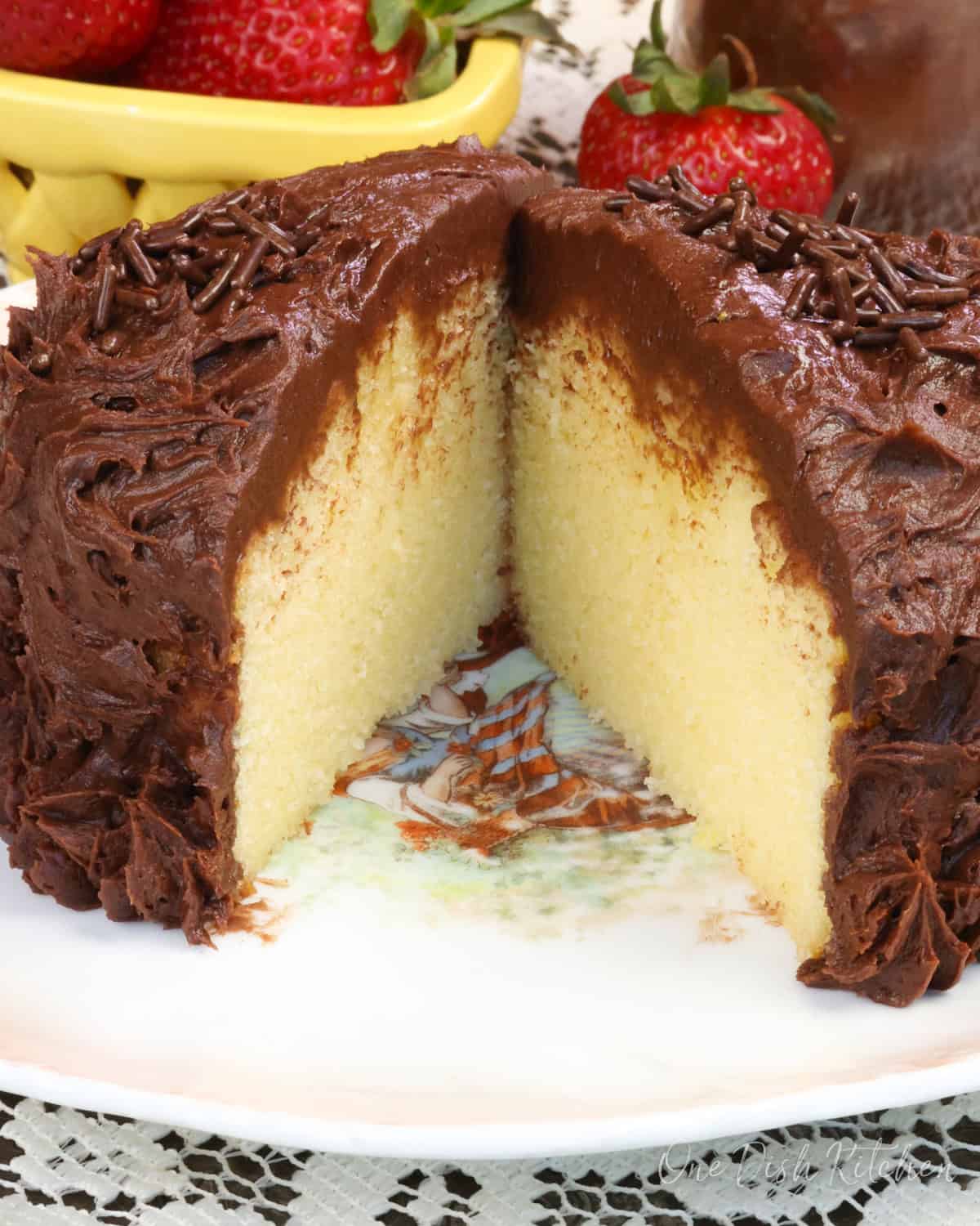 a small yellow cake topped with chocolate buttercream on a white plate.