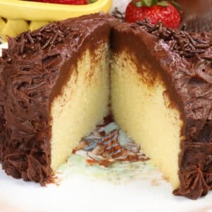 a small yellow cake topped with chocolate buttercream on a white plate.