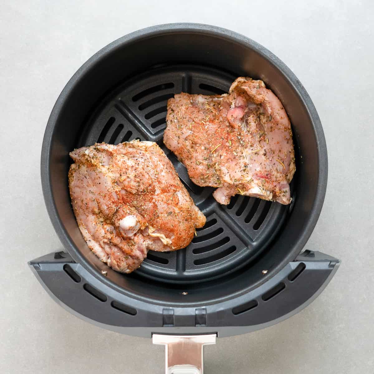 two bone in, in skin on chicken thighs in an air fryer.