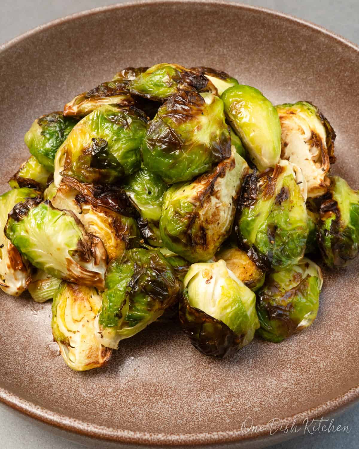 a small batch of air fryer brussels sprouts on a brown plate.