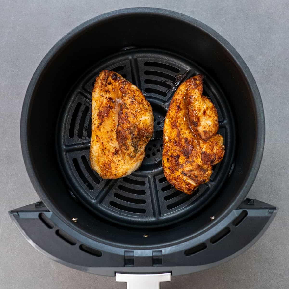 two chicken breasts in an air fryer.