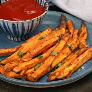 sweet potato fries on a blue plate with ketchup.