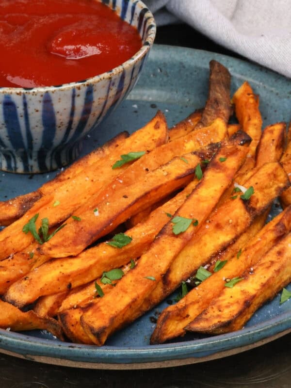 sweet potato fries on a blue plate with ketchup.
