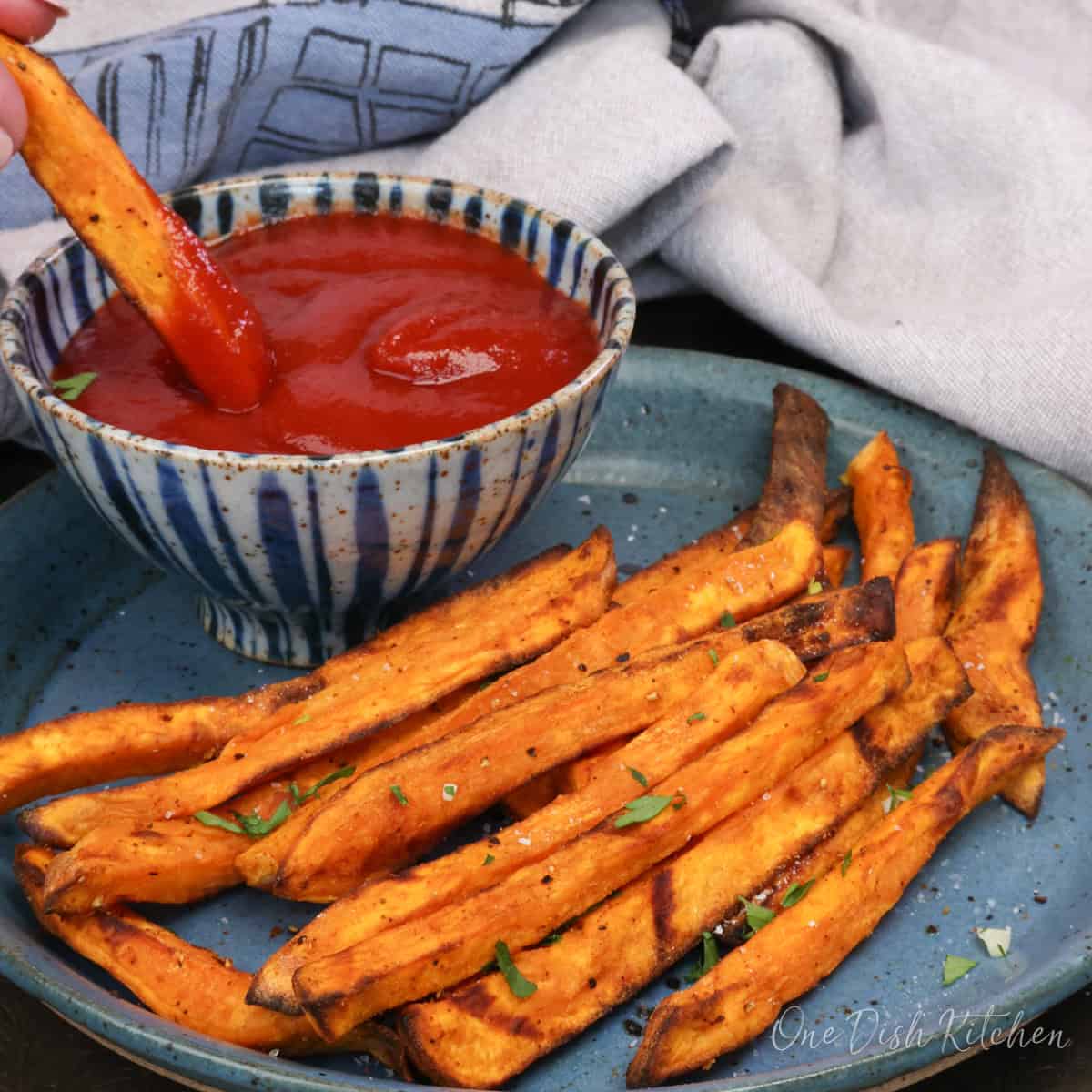sweet potato fries on a blue plate with ketchup.