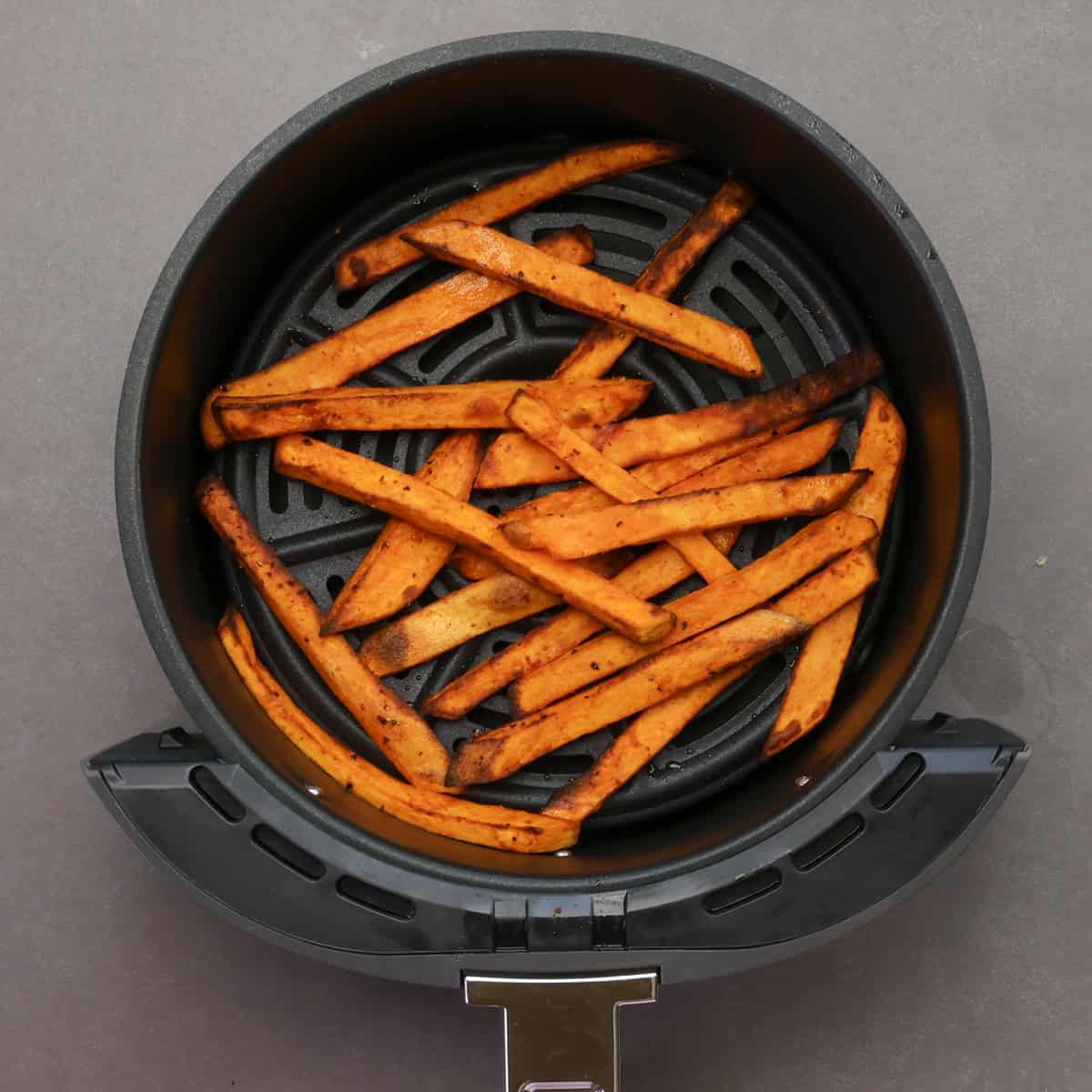 sweet potato fries in an air fryer basket.
