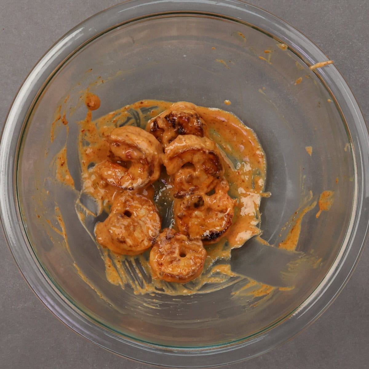 cooked shrimp tossed in bang bang sauce in a bowl.