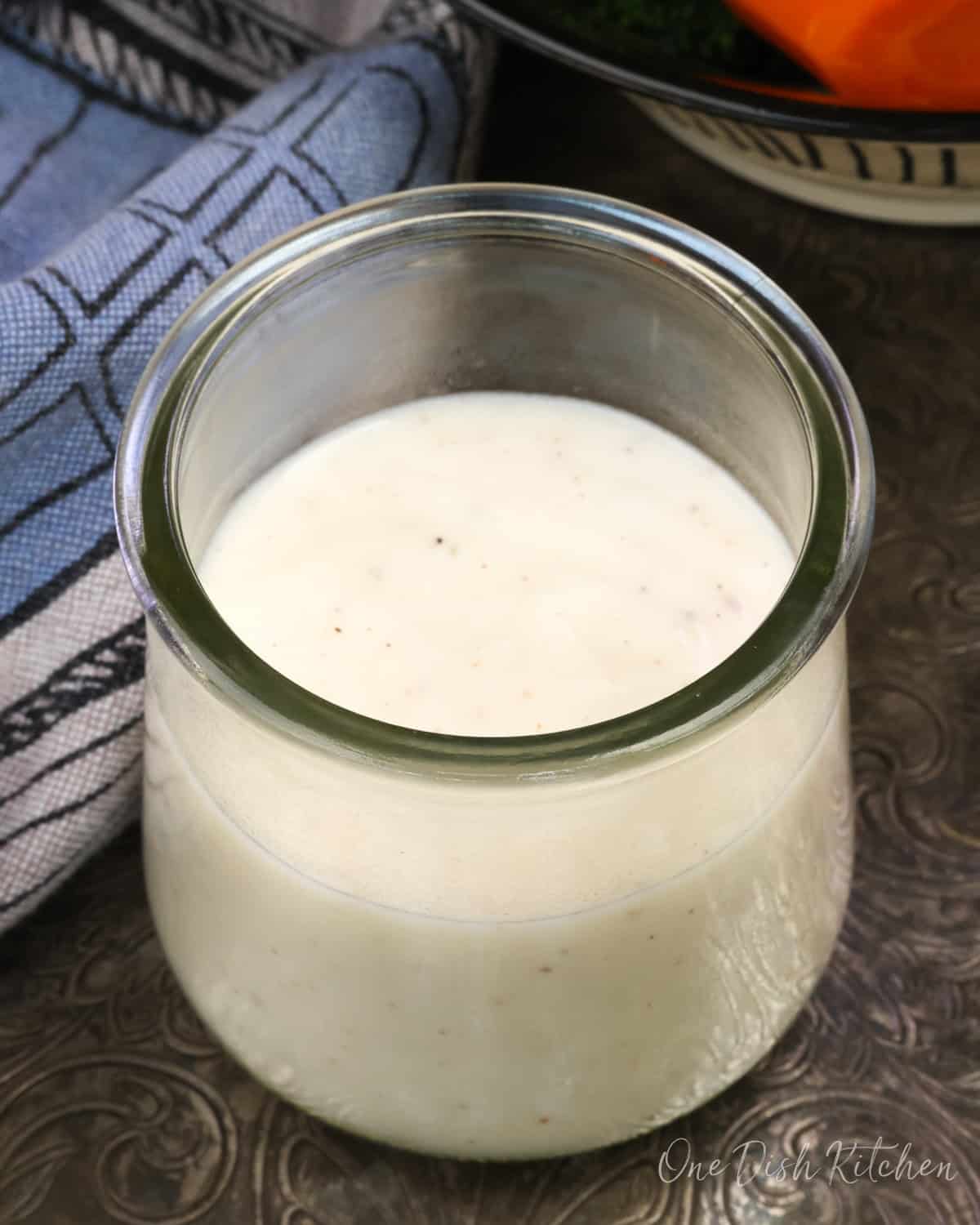 a small jar of bechamel sauce on a silver tray.
