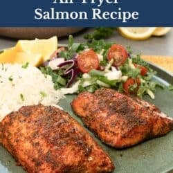 two air fryer salmon fillets on a green plate next to rice and a salad.