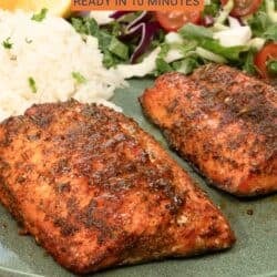two air fryer salmon fillets on a green plate next to rice and a salad.