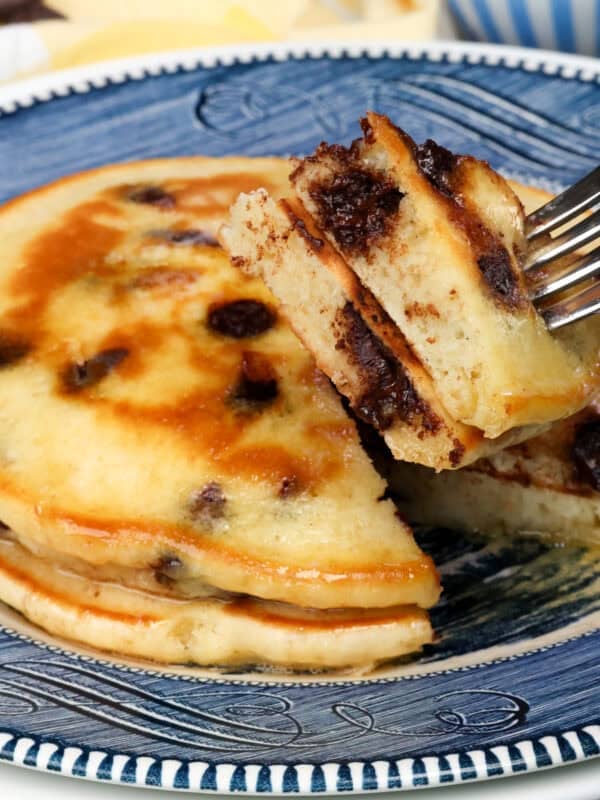 two fluffy chocolate chip pancakes on a blue plate with a fork on the side.