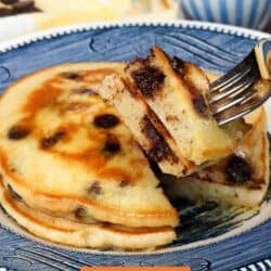 two fluffy chocolate chip pancakes on a blue plate with a fork on the side.