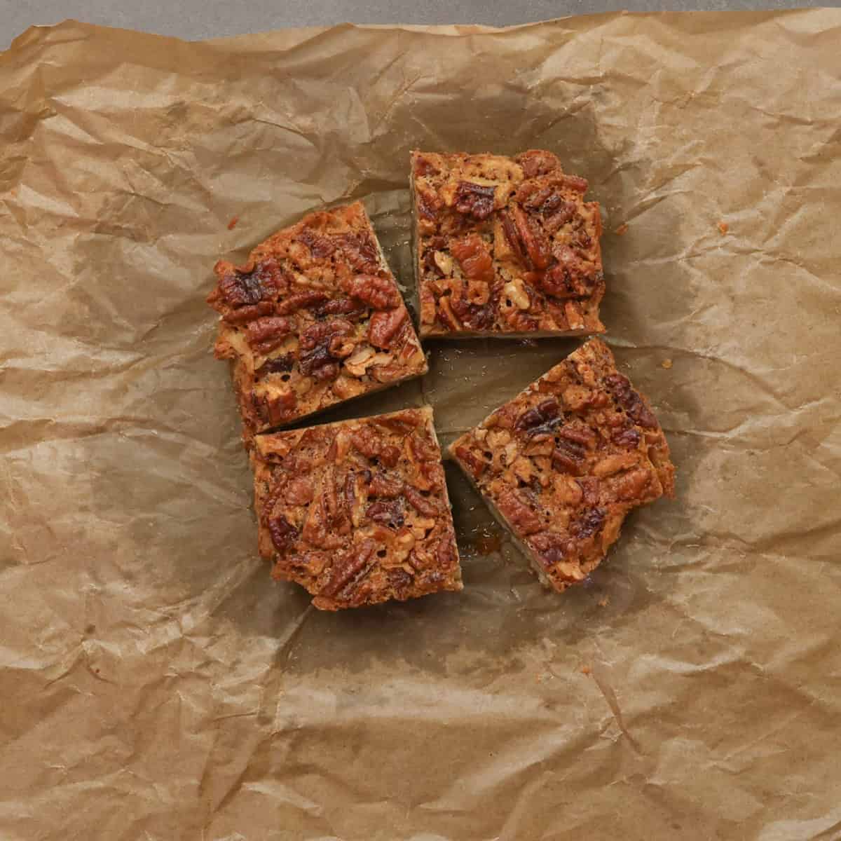 pecan pie bars cut into 4 squares on parchment paper.