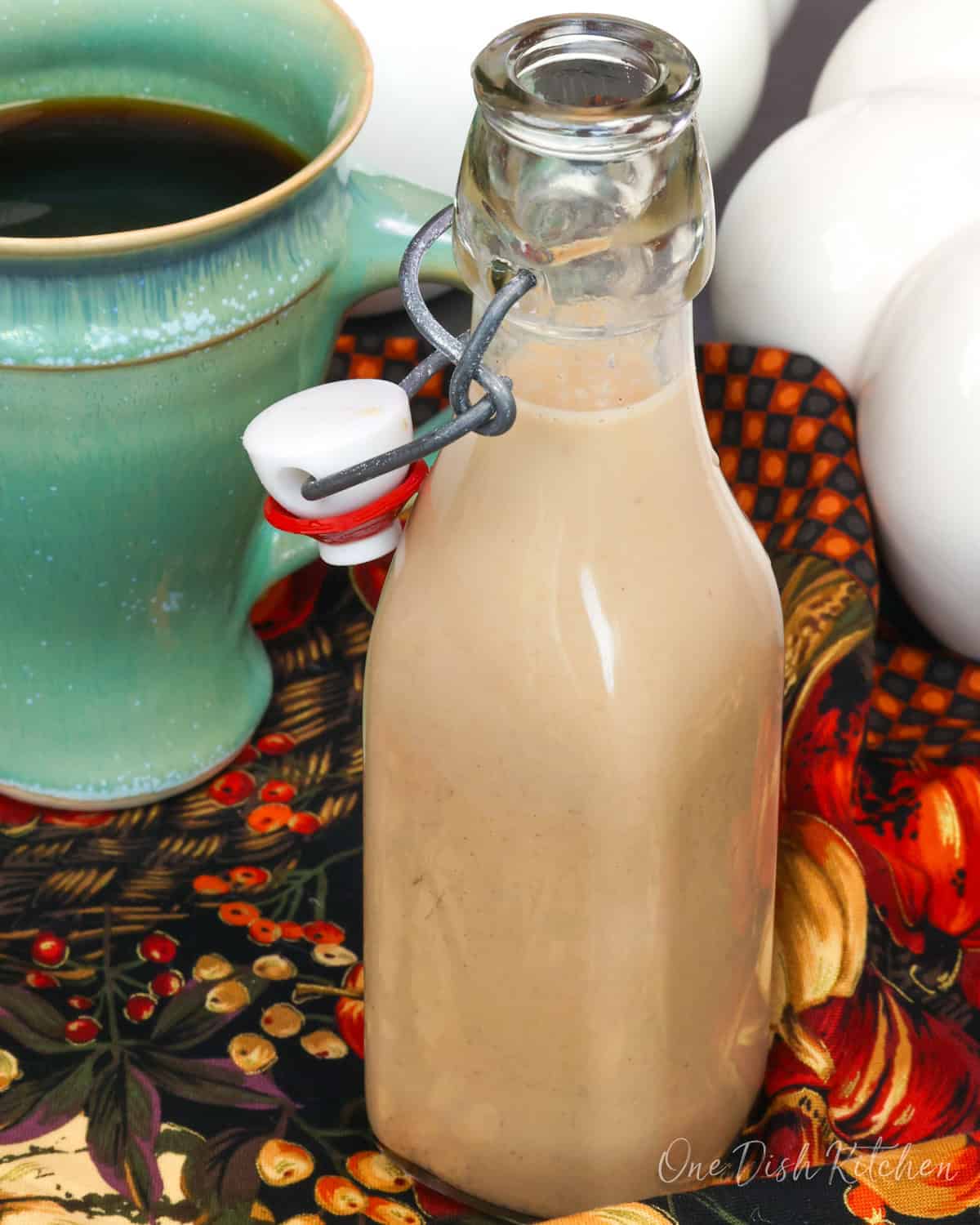 a small batch of pumpkin spice creamer next to a cup of coffee.
